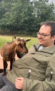 a picture of sebastian sitting on a bench surrounded by goats